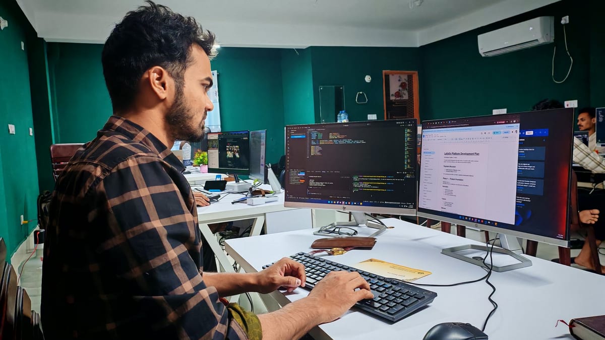 A developer at a dual-monitor desk with code on the screens